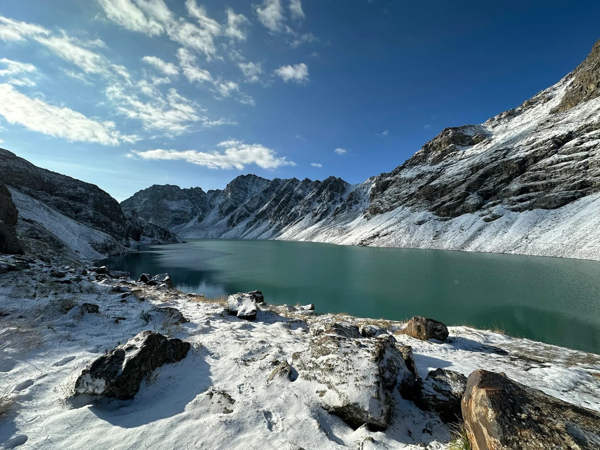 Ala-Kul lake below snow-covered mountain ridges